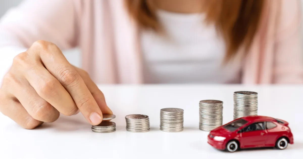 A small red model car in front of stacks of coins