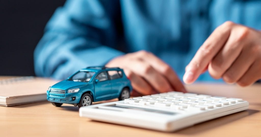 A small model blue car next to a calculator