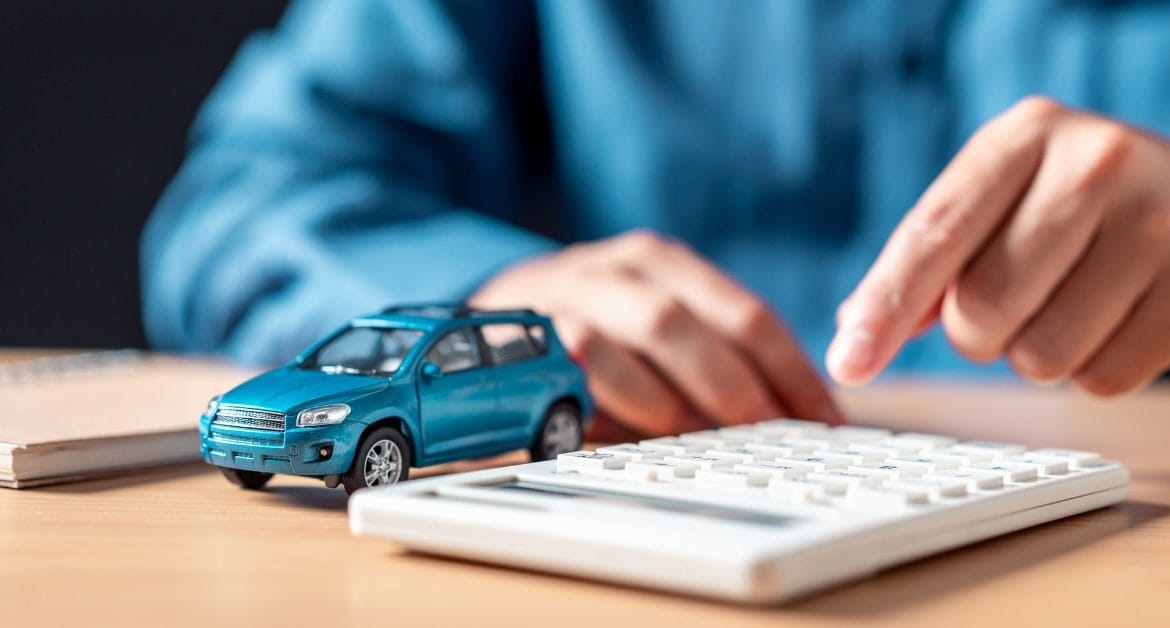 A small model blue car next to a calculator
