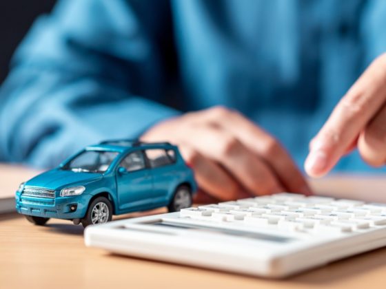 A small model blue car next to a calculator