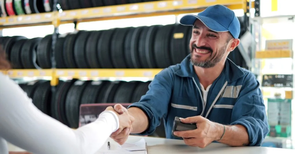 Smiling mechanic shaking hands with a customer in a tyre shop