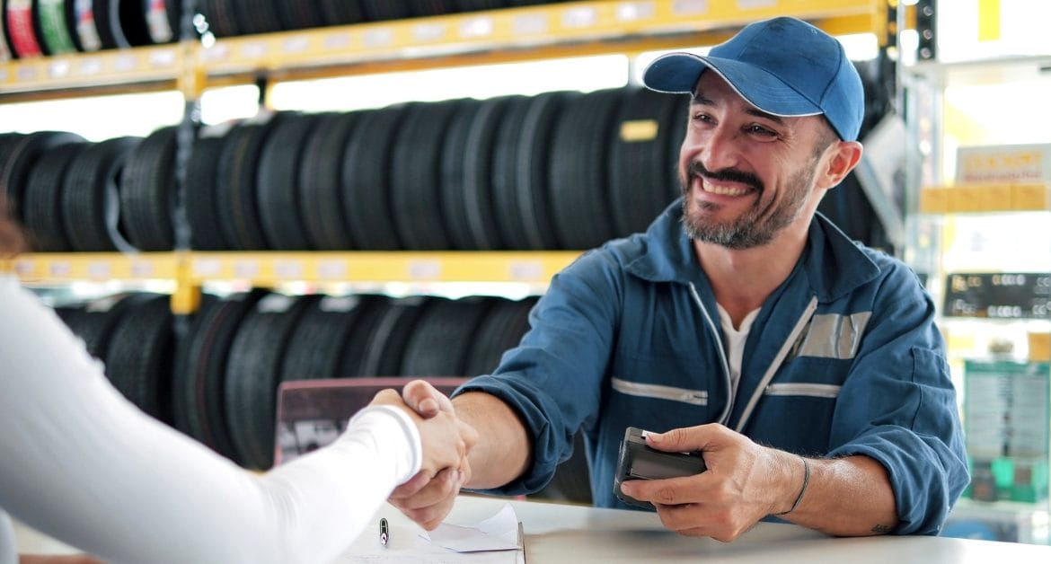 Smiling mechanic shaking hands with a customer in a tyre shop