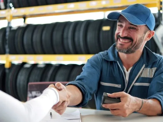 Smiling mechanic shaking hands with a customer in a tyre shop