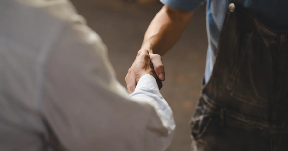 Close-up of a handshake between a mechanic and a customer, symbolising trust and agreement on car repairs or service.