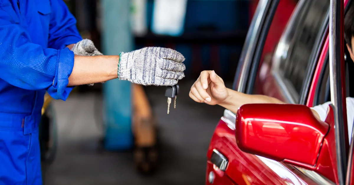Mechanic handing car keys to customer in a red vehicle, representing buy now pay later car repairs