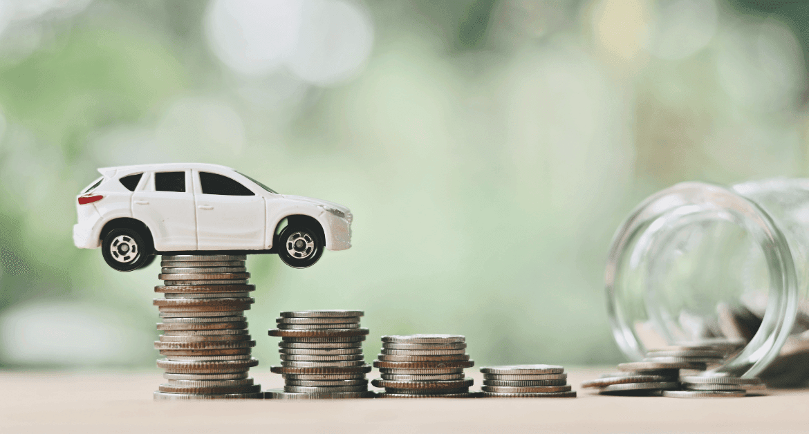 White toy SUV balanced on stacked coins with a jar spilling coins, representing cost of running a car and saving money.