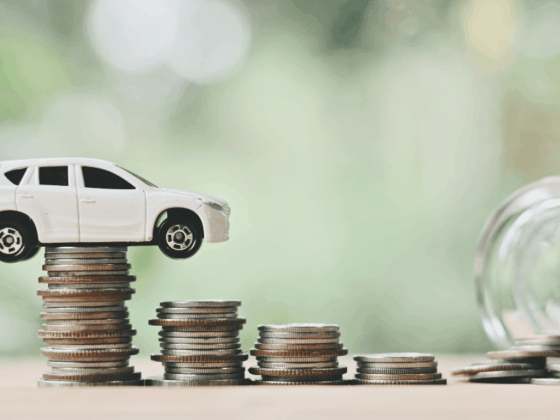 White toy SUV balanced on stacked coins with a jar spilling coins, representing cost of running a car and saving money.