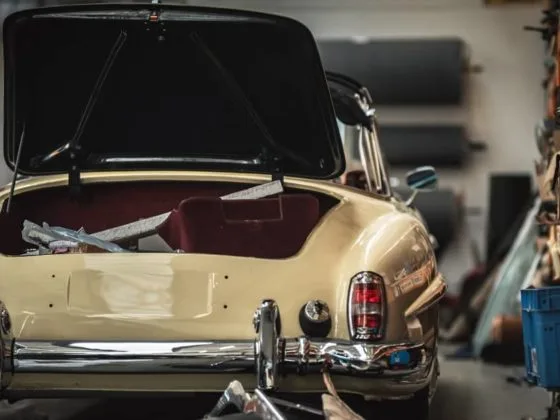 Classic cream car with open boot in a workshop, showing the impact of car repairs on the lifespan of a car, particularly for older vehicles facing higher maintenance needs.