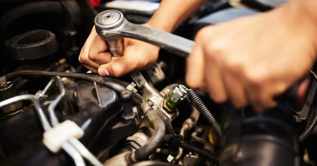 Close-up of a mechanic using a ratchet tool on an engine, showing engine repairs as one of the most common car repairs that adds to the overall cost of car repairs.
