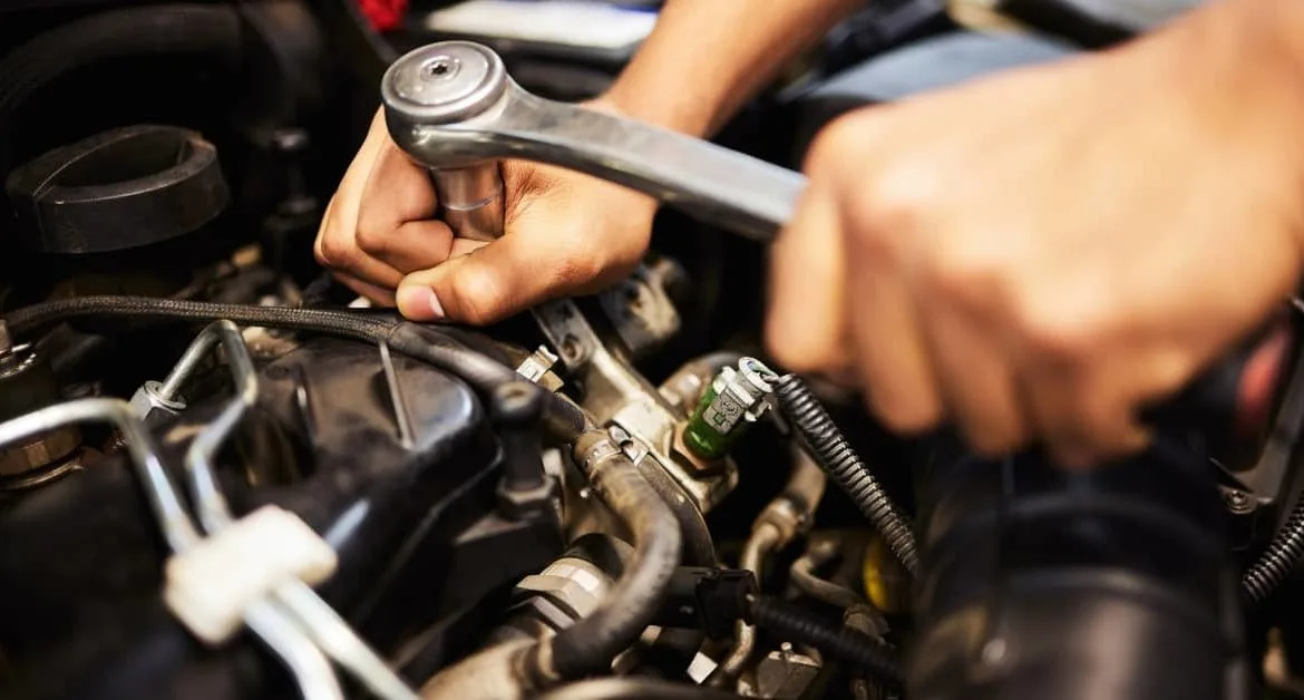 Close-up of a mechanic using a ratchet tool on an engine, showing engine repairs as one of the most common car repairs that adds to the overall cost of car repairs.