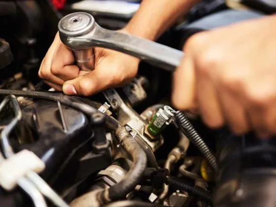 Close-up of a mechanic using a ratchet tool on an engine, showing engine repairs as one of the most common car repairs that adds to the overall cost of car repairs.