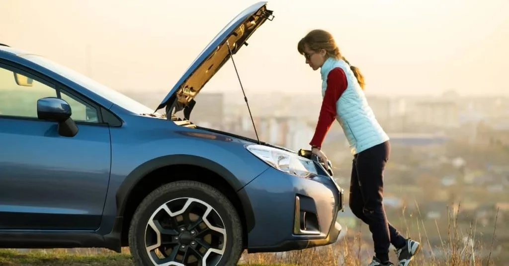 Young driver delaying car repairs while checking a broken-down vehicle, concerned about car repair costs.