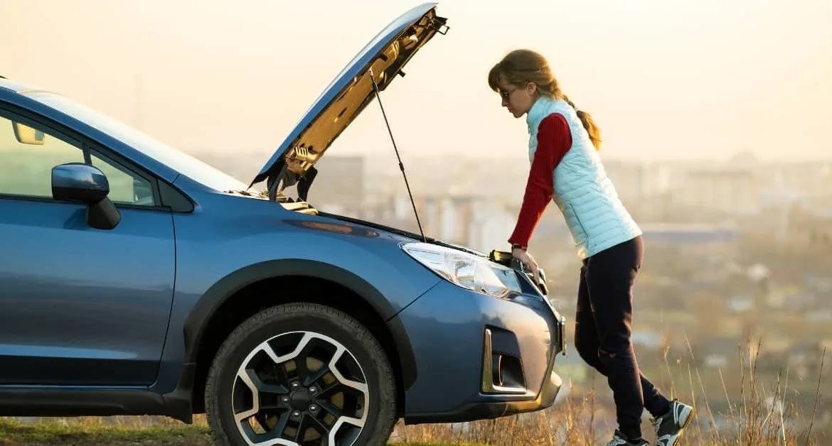 Young driver delaying car repairs while checking a broken-down vehicle, concerned about car repair costs.