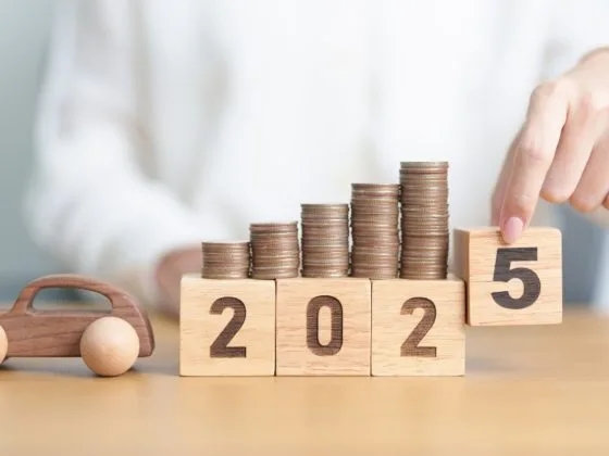 A row of coins stacked on wooden blocks marked 2025, used to show how the UK Budget could influence motoring costs and the automotive sector in the year ahead.
