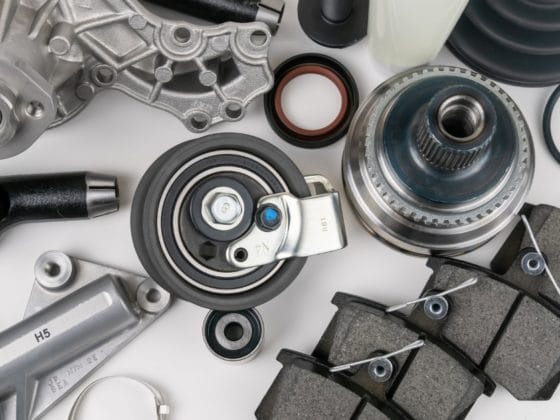 Car parts shortage: Flat lay of assorted car parts including brake pads, bearings and mechanical components laid out on a white background.