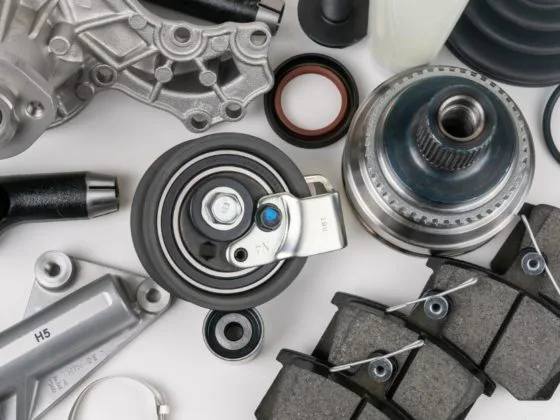 Car parts shortage: Flat lay of assorted car parts including brake pads, bearings and mechanical components laid out on a white background.