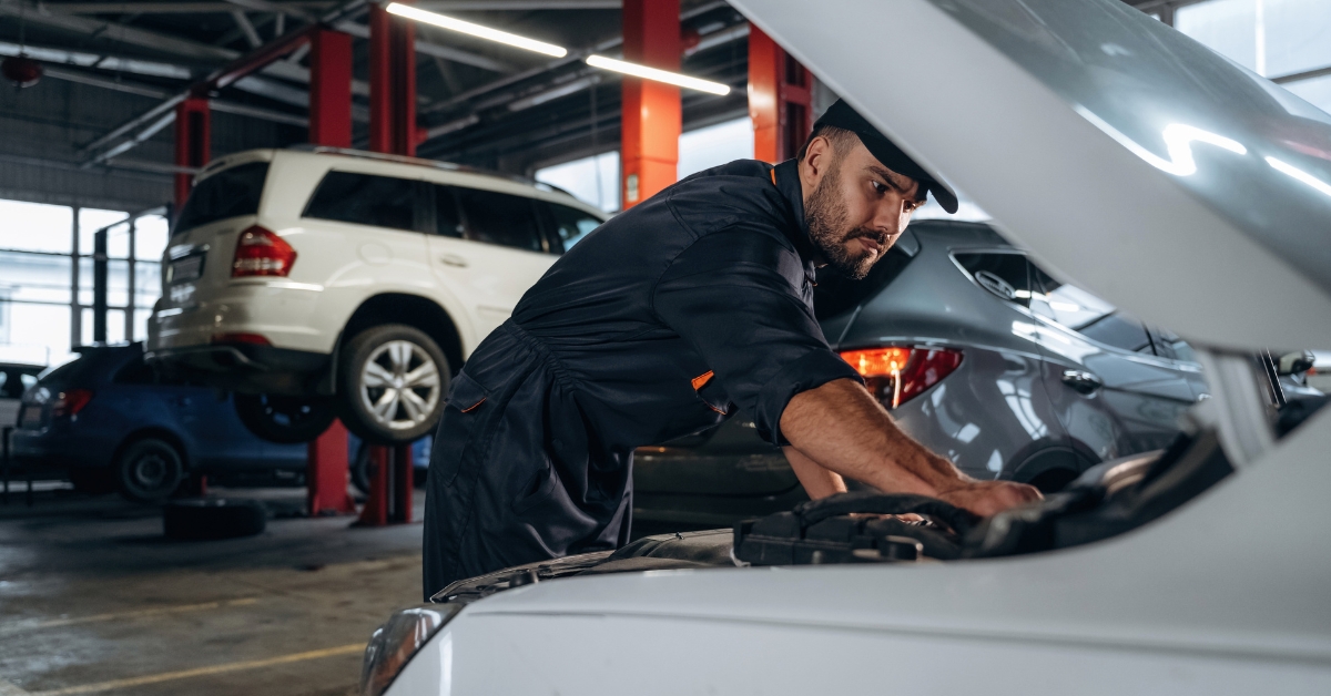 Spread the cost of car repairs, Mechanic working under a car bonnet in a workshop, representing the option to spread the cost of car repairs.
