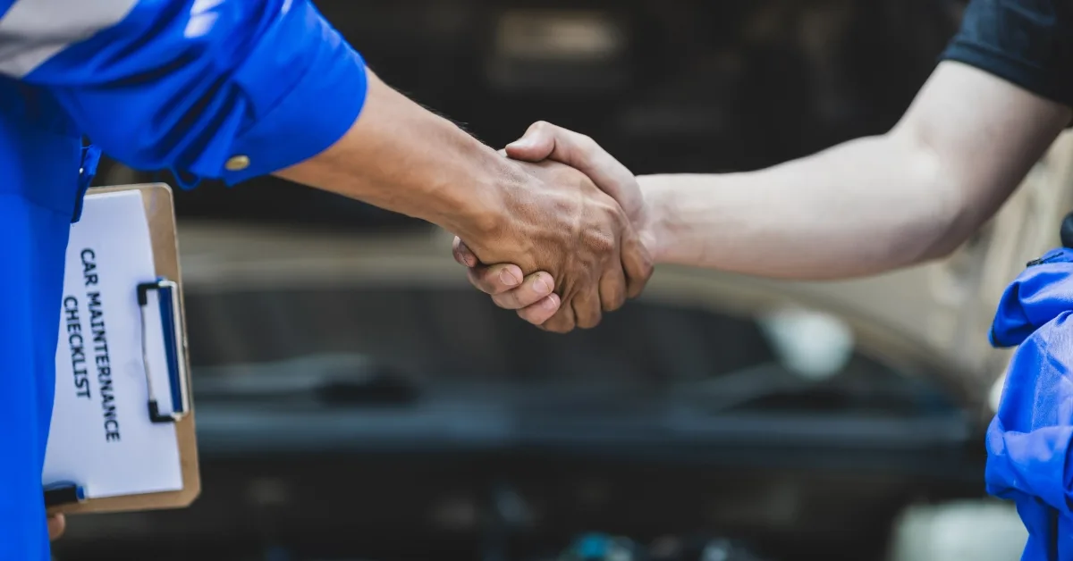 Spread the cost of car servicing, Two people shaking hands beside a clipboard labelled car maintenance checklist, representing agreement to spread the cost of car servicing.