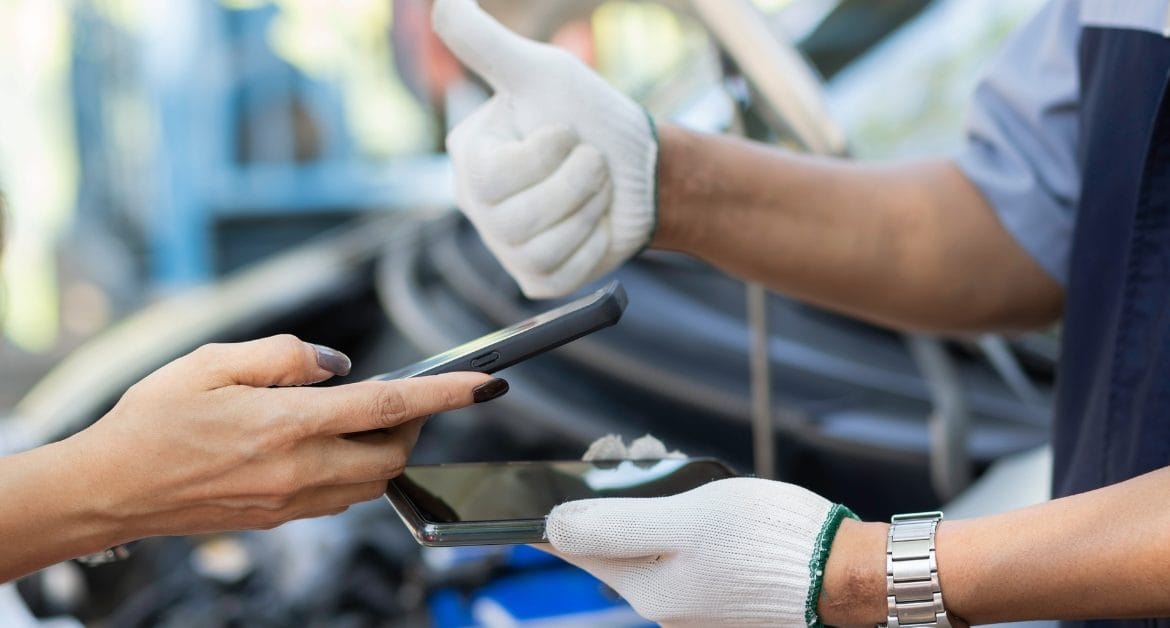 Responsible BNPL for car repairs, Mechanic giving a thumbs up while a customer holds a smartphone, symbolising responsible BNPL for car repairs and digital payment approval.