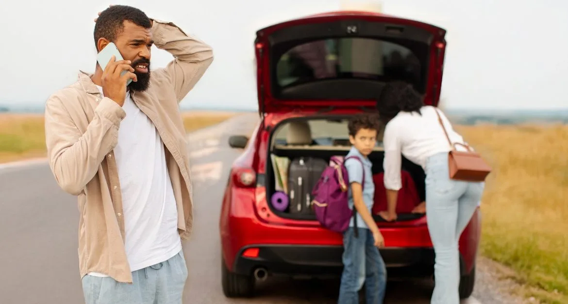 Car repair help for families – Parent on the phone beside a broken-down car while family members stand at the open boot.