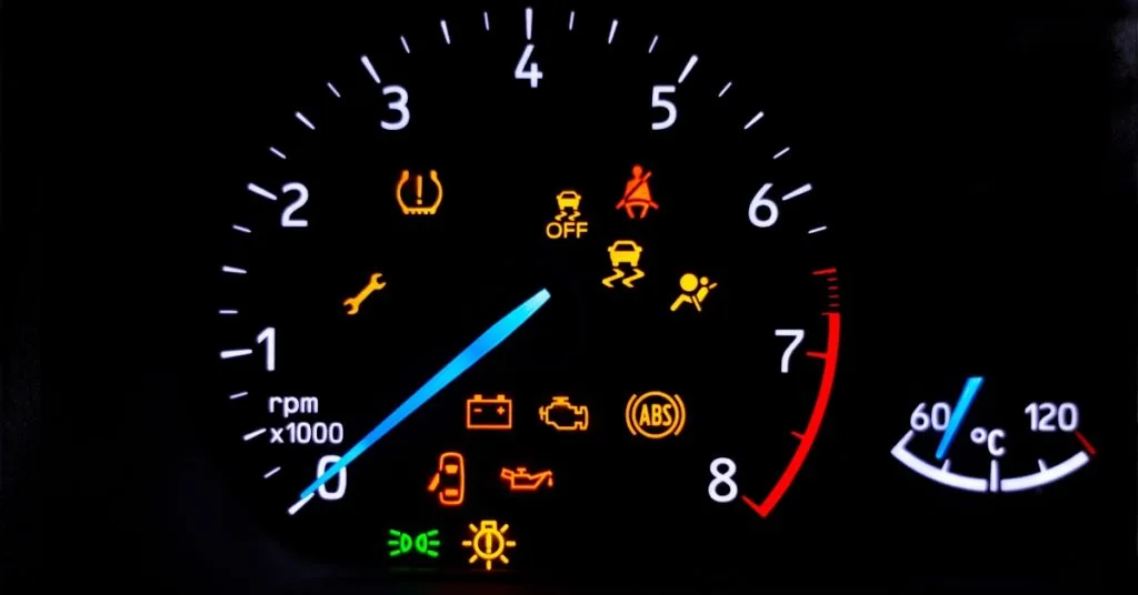 Car warning signs – Car dashboard with illuminated warning lights including tyre pressure, ABS, engine, oil, and seatbelt alerts.