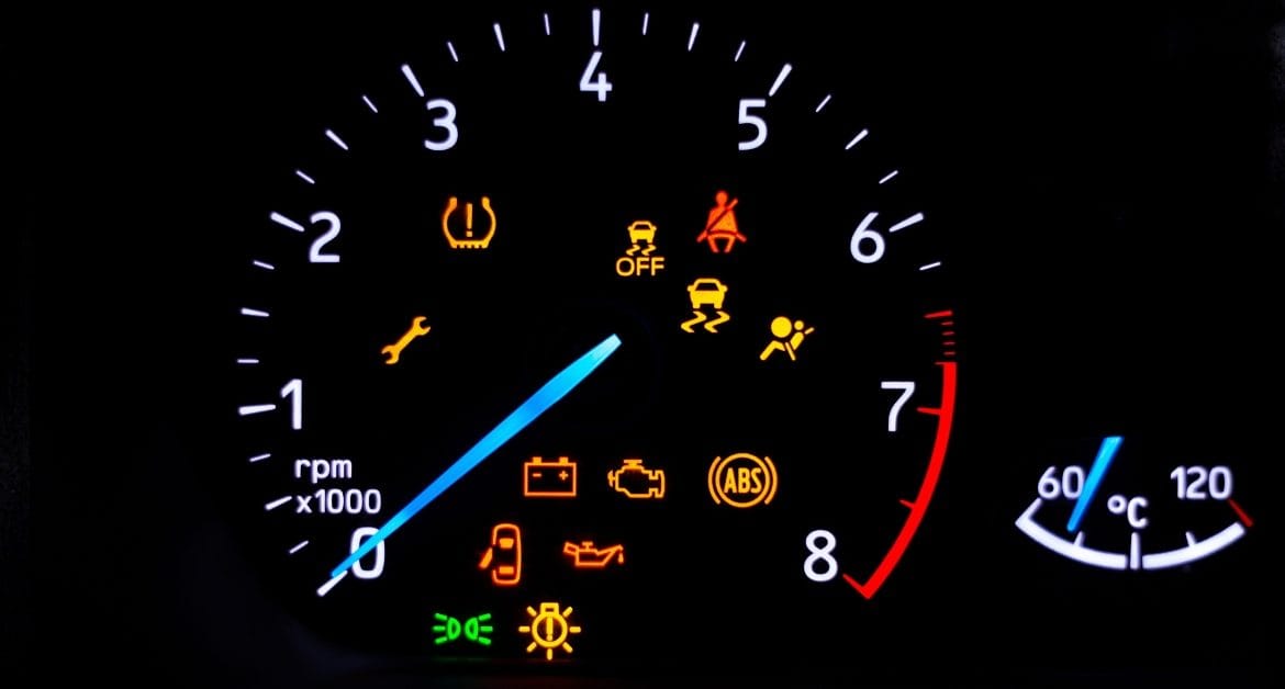 Car warning signs – Car dashboard with illuminated warning lights including tyre pressure, ABS, engine, oil, and seatbelt alerts.